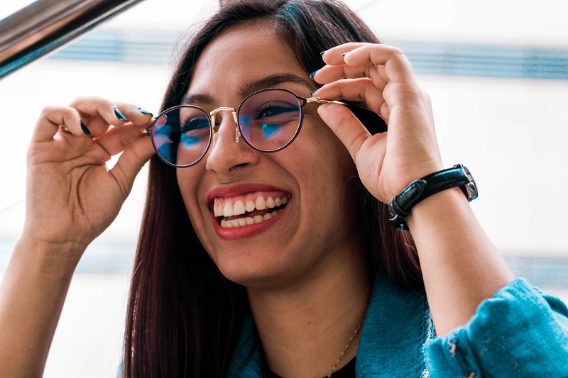 person smiling while adjusting eyeglasses